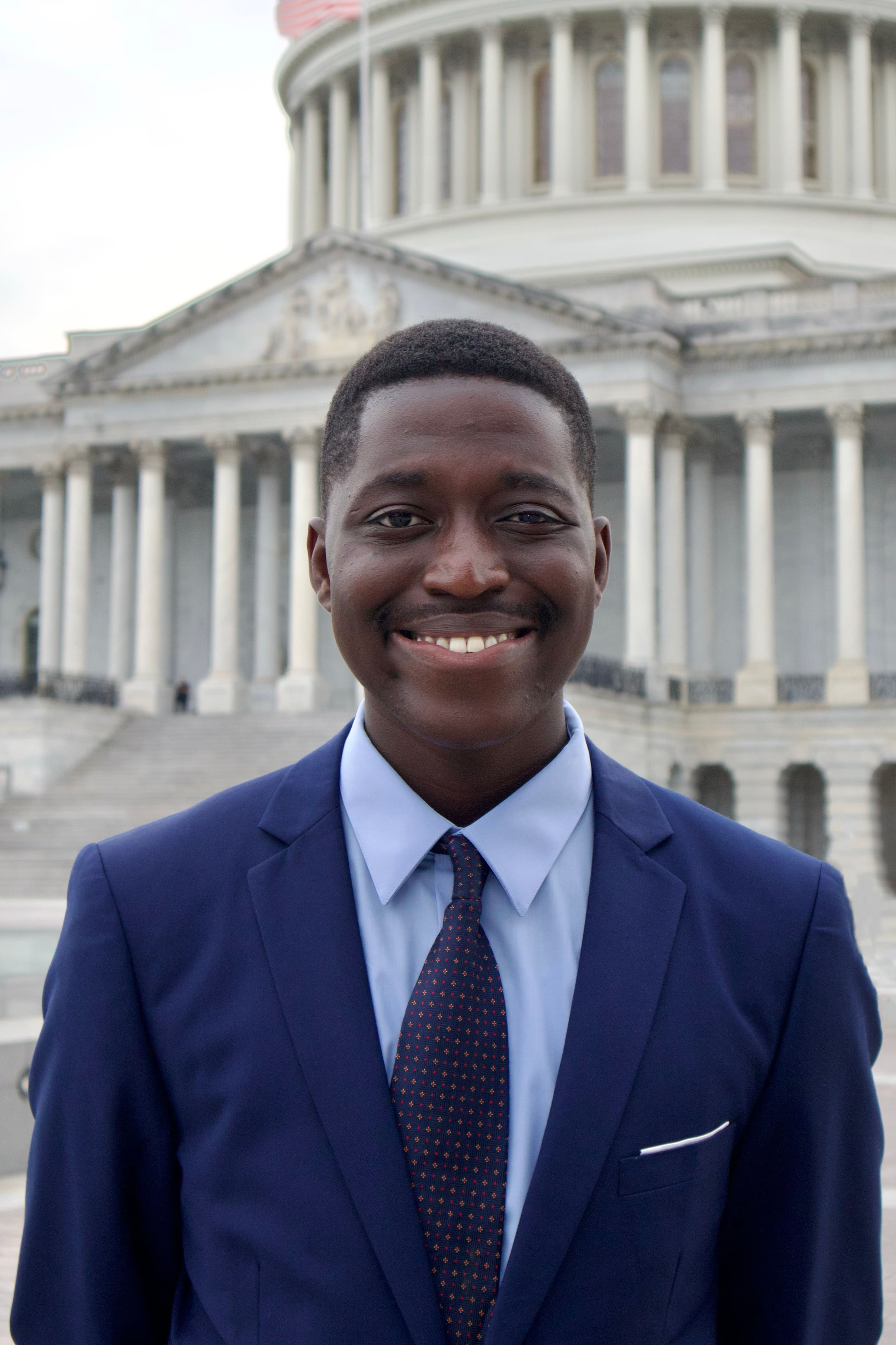 Photo of a man in a suit at the Capitol, smiling