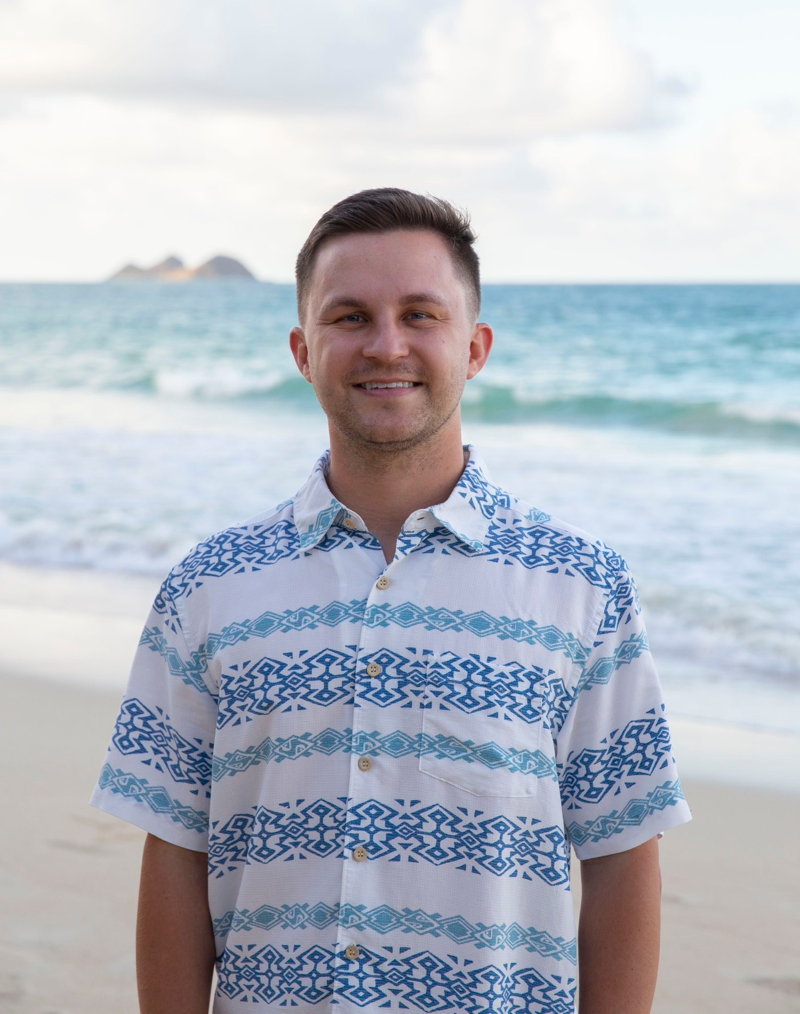 Photo of a man in an aloha shirt at the beach, smiling
