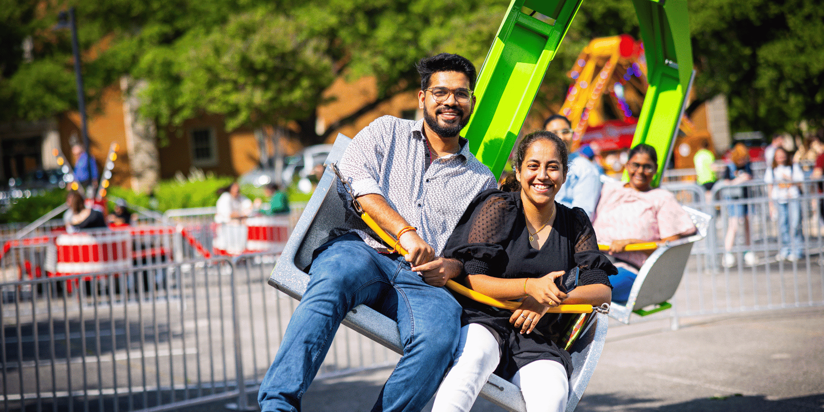 two people sitting on a swinging ride