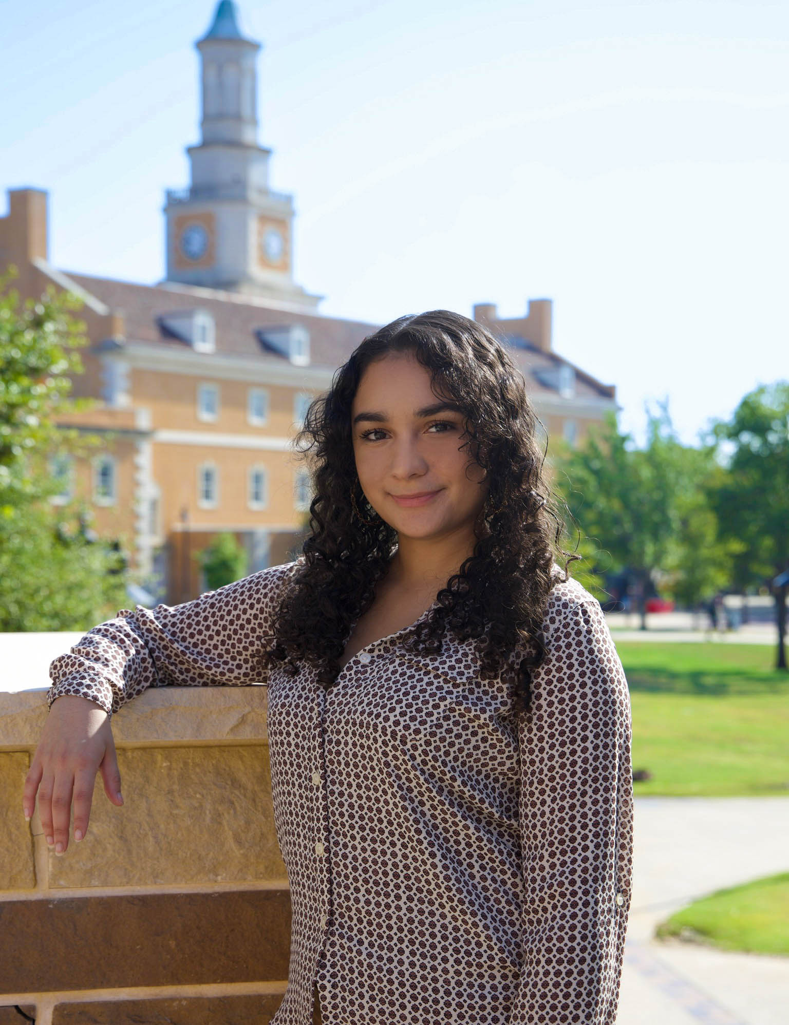 person smiling with arm on ledge infront of admin building