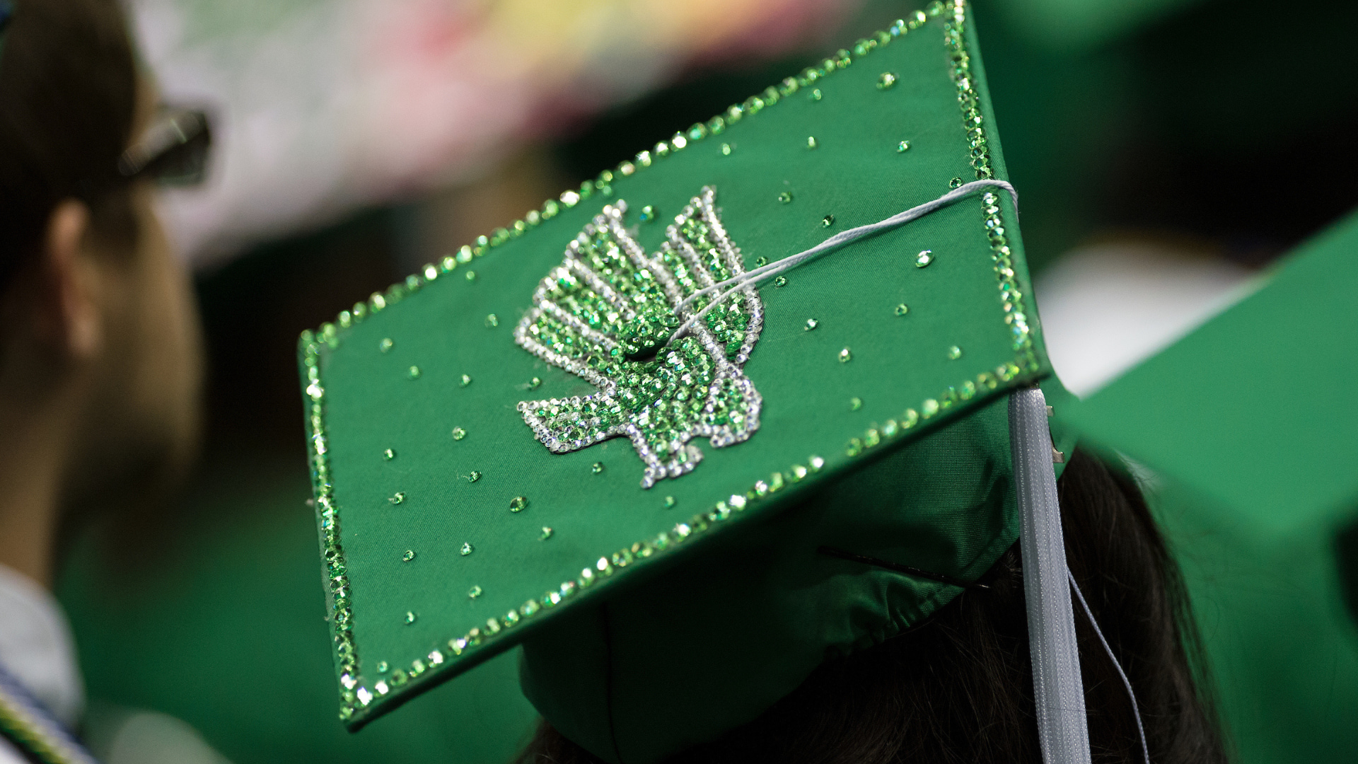 A green graduation cap with a green eagle in the center of the cap