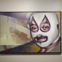 Person with a white and purple wrestling mask in front of an abstract background