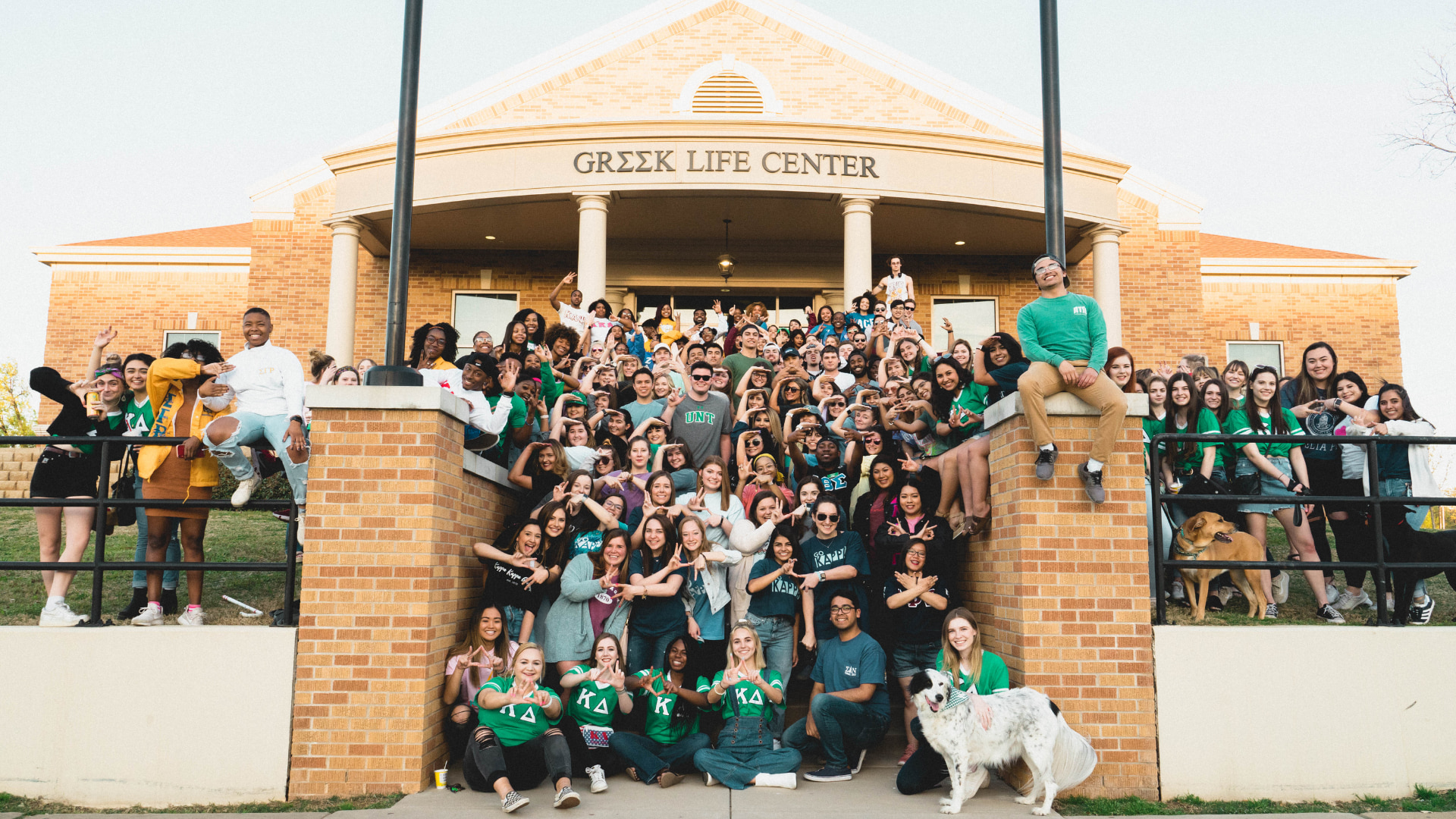 Students posing outside of the Greek Life Center, smiling