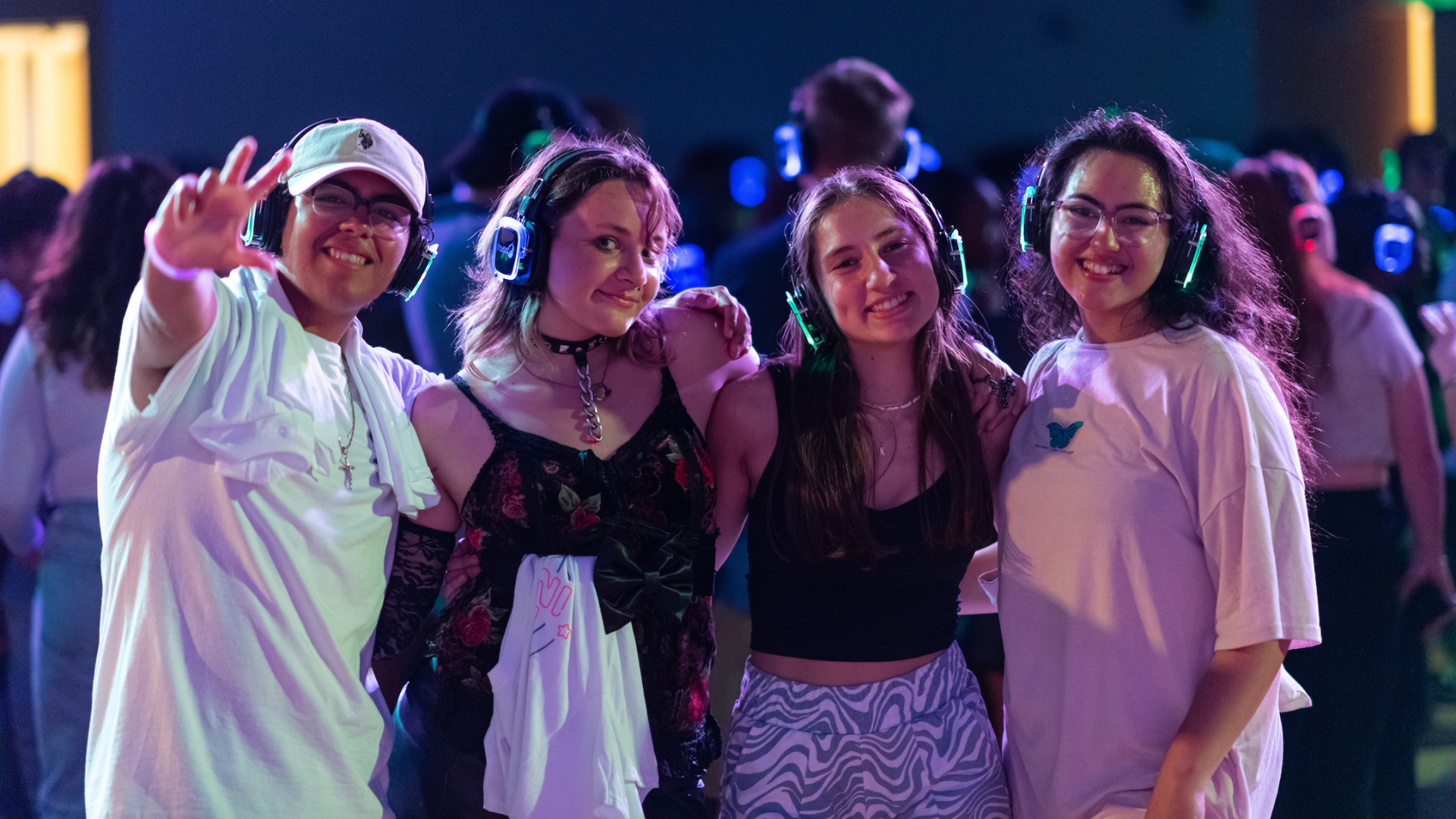 Students smiling and posing for a photo, at Silent Disco, wearing headphones