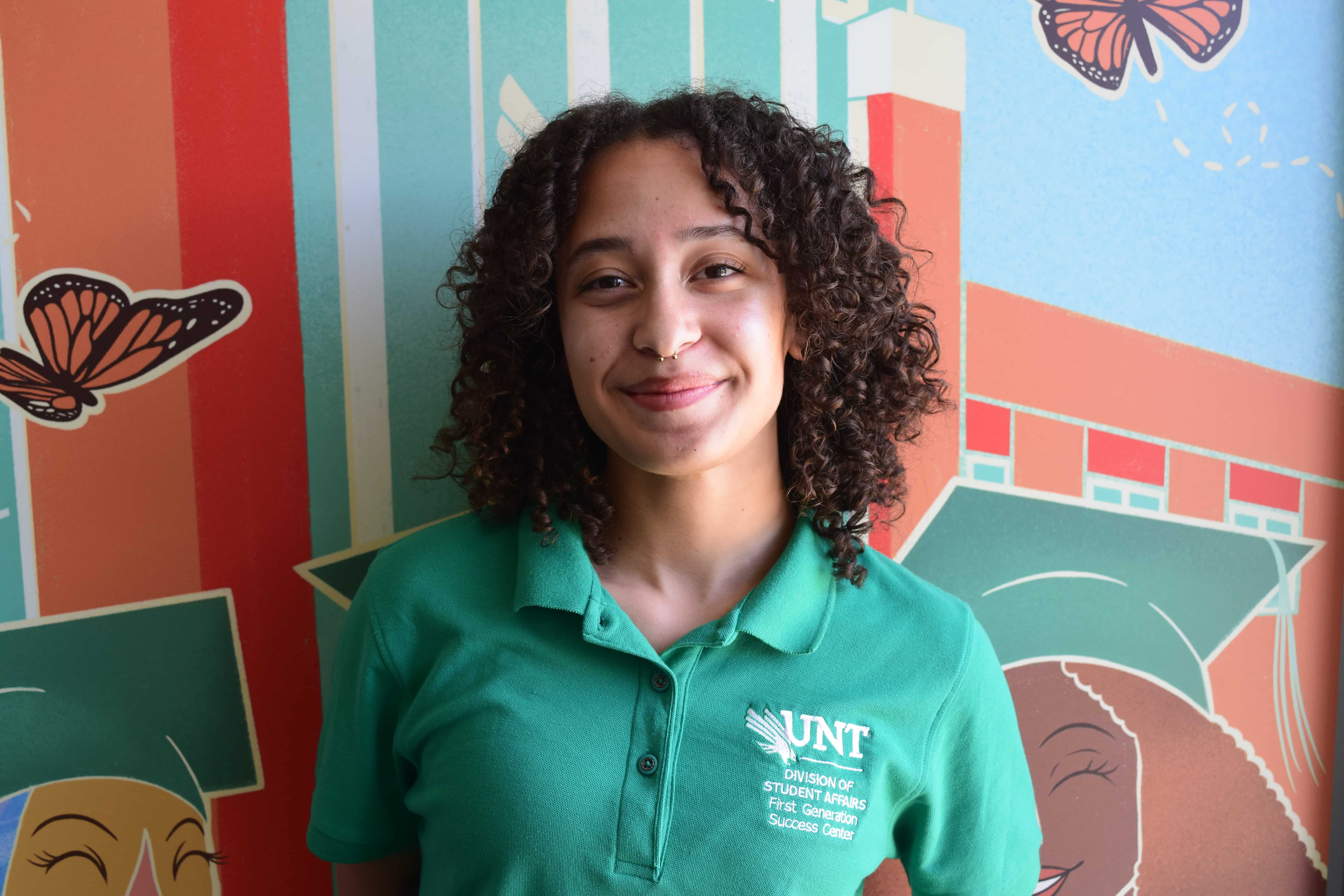 Student smiling in front of colorful mural