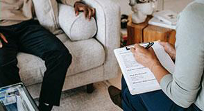 person sitting on couch talking to another person taking notes