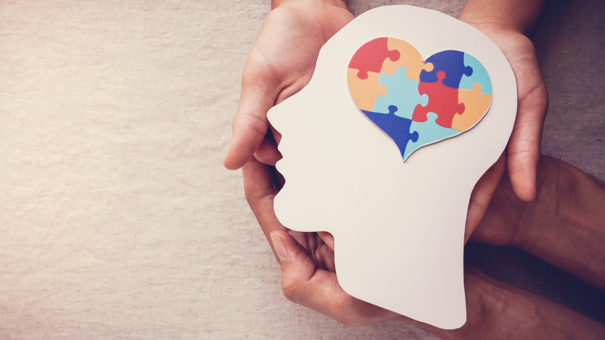 image of hands holding a face silhouette with a heart puzzle as the brain