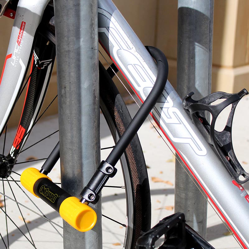 yellow and black bike lock is locked around a grey bike