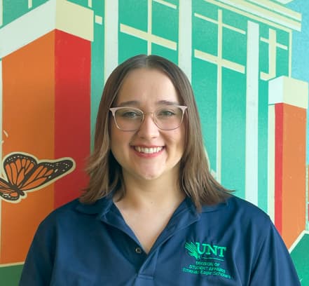 Person smiling in front of colorful mural