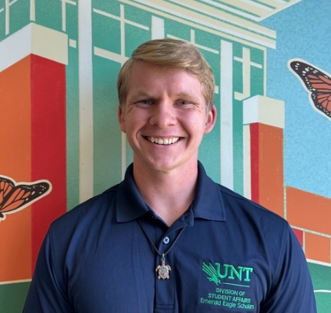 Student smiling in front of colorful mural