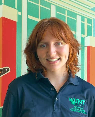 Student smiling in front of colorful mural