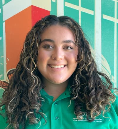 Student smiling in front of colorful mural
