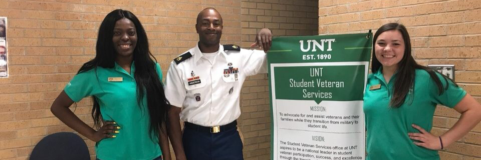 Green Jackets standing with Student Veteran Services Sign