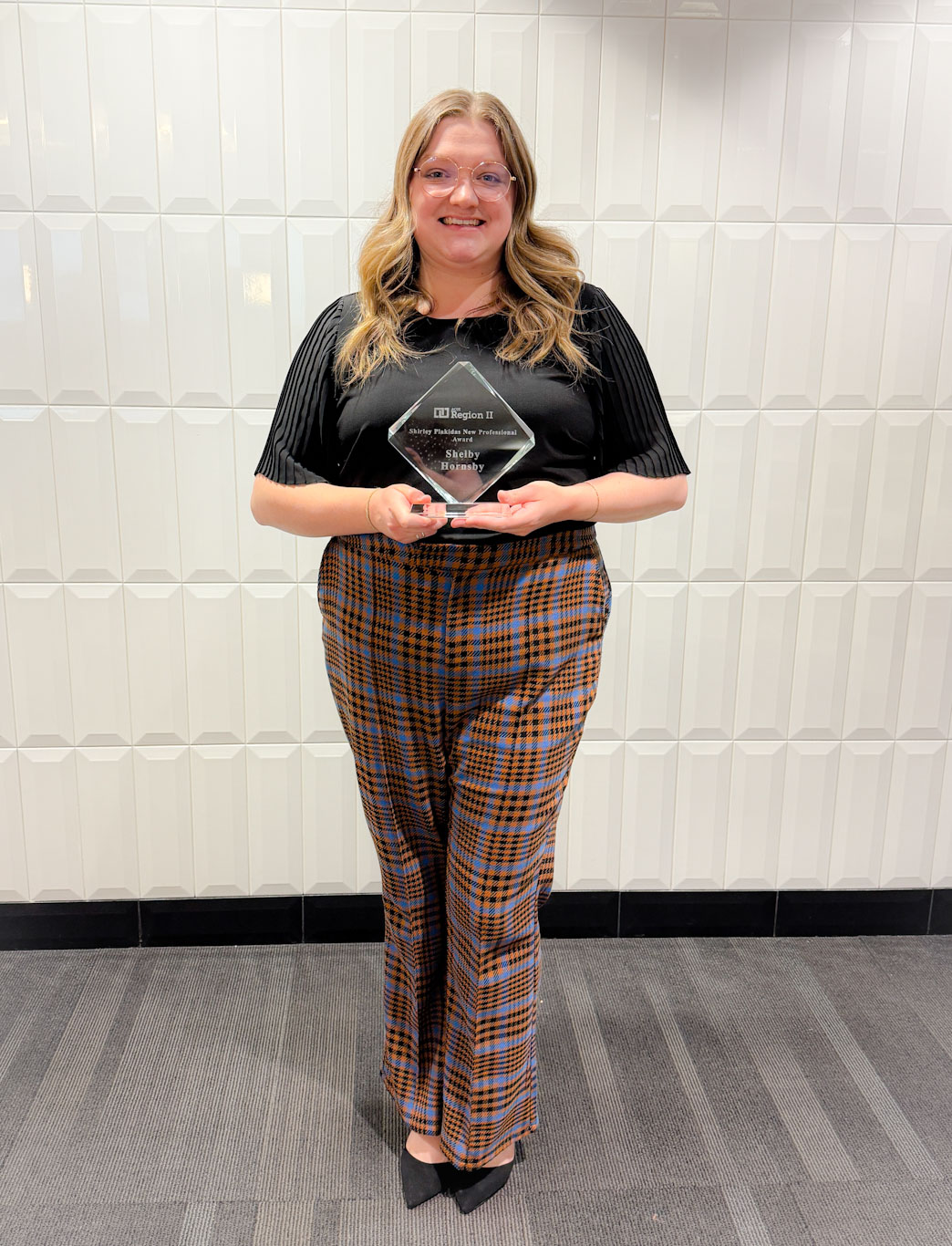 A photo of Shelby holding the ACUI Award.