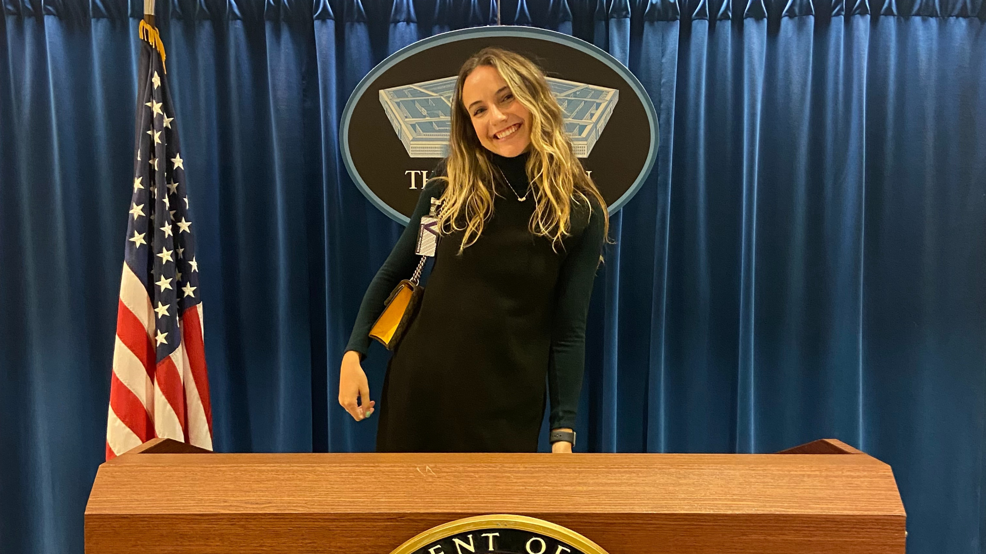 Student standing in front of Department of Defense podium, smiling