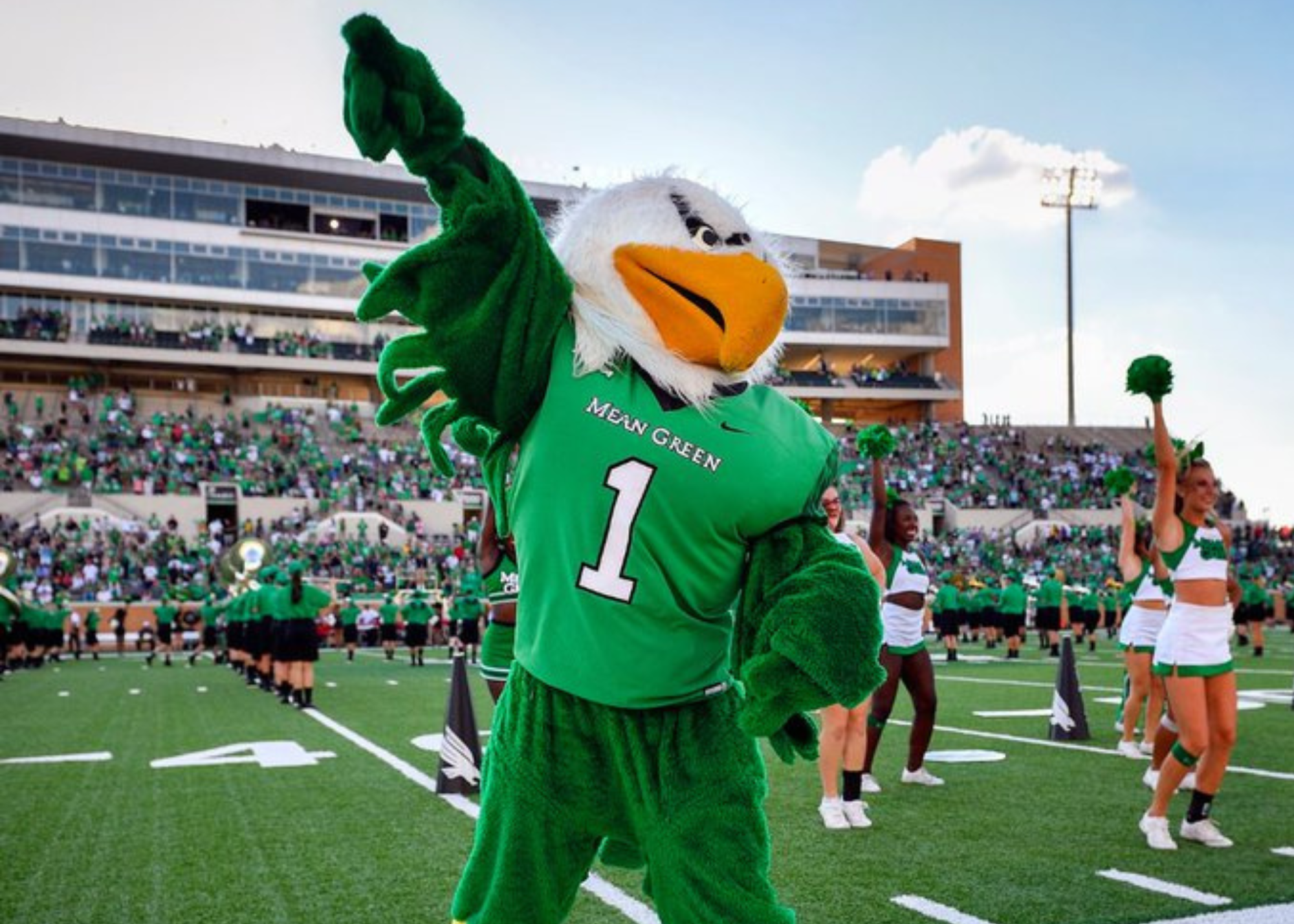 Picture of Scrappy mascot on the Datcu Stadium football field with the UNT cheerleaders.