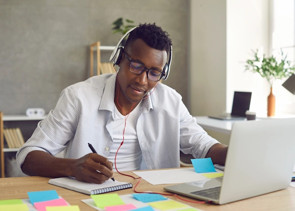 Student sitting at desk with computer, notebook, and post it notes.
