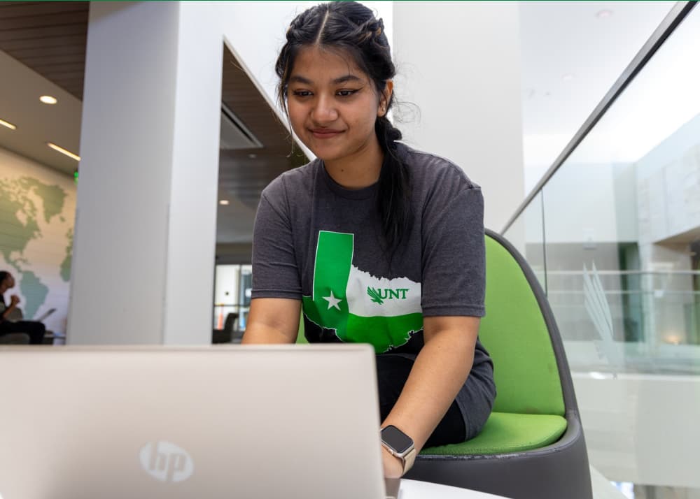 Photo of a peer mentor working on a laptop and smiling