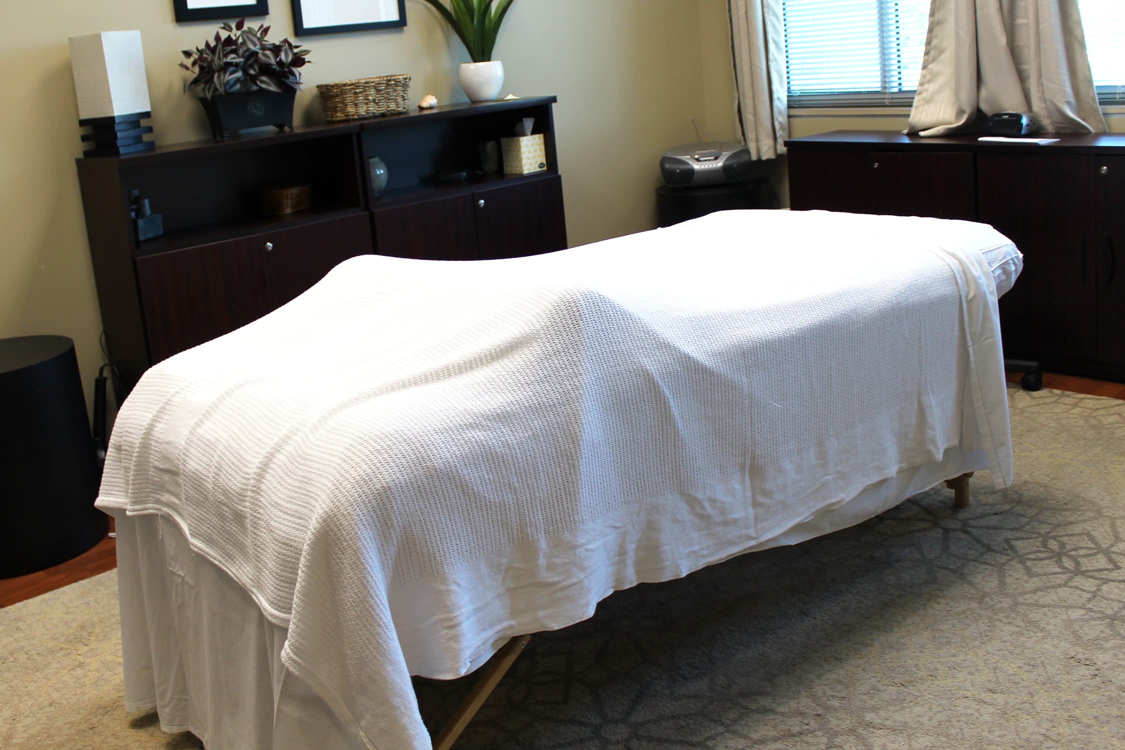 Massage table draped with white linens in the massage therapy suite located in the SHWC Office of Health Promotion.