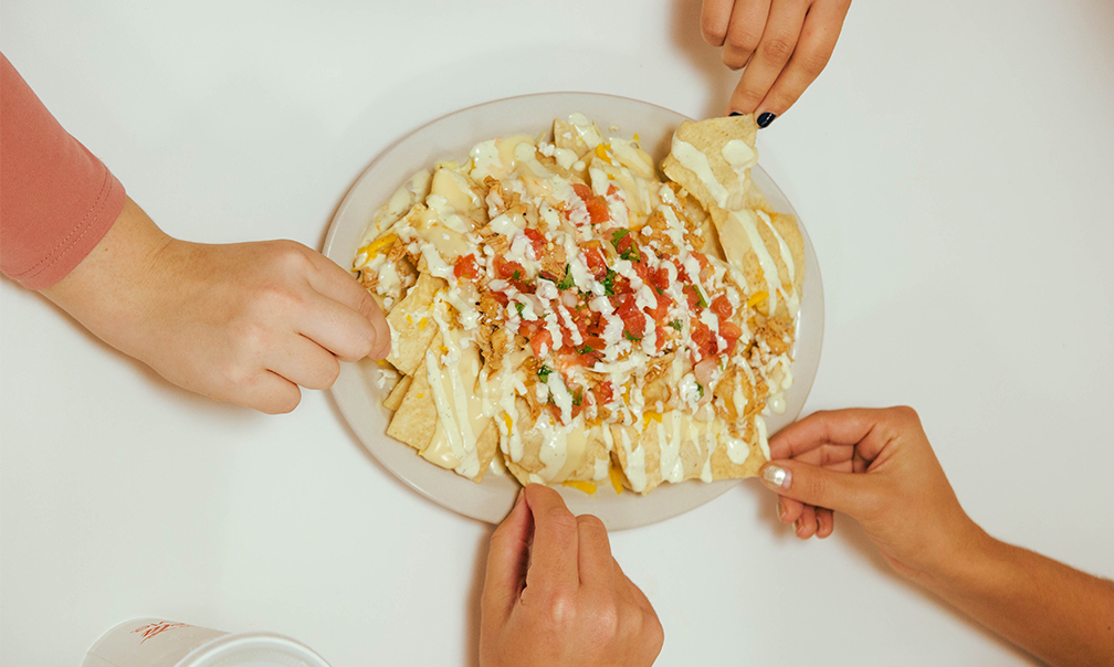 Four Students Sharing A Plate Of Nachos