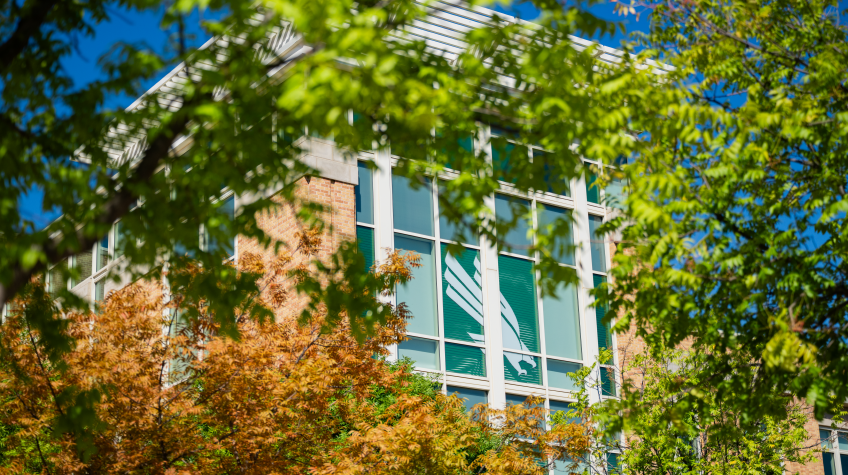 Image of the University Union close up framed by green and golden brown leaves 