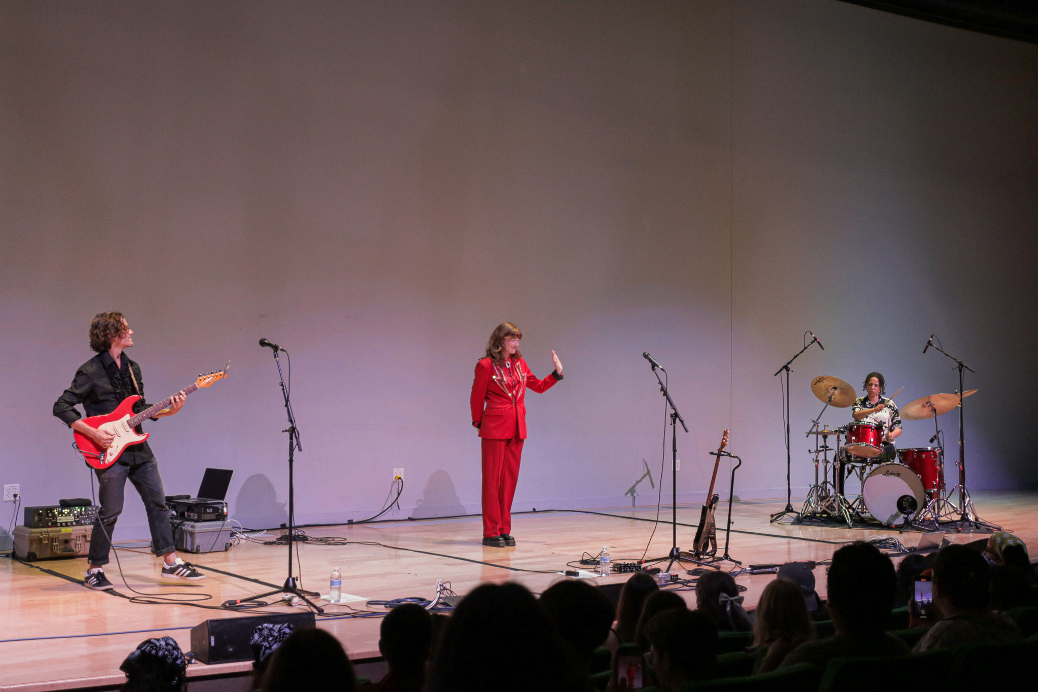 Allison Ponthier performs on stage, wearing a red outfit while waving at the crowd. Allison Ponthier