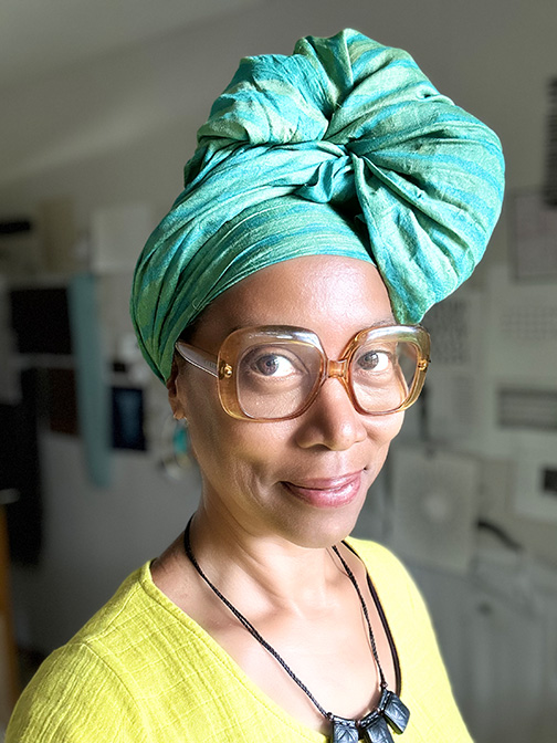 image of visual artist sonya clark with a head scarf, glasses, and a bright green shirt